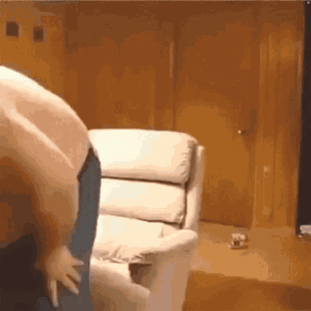 a man is standing in front of a white recliner in a living room .