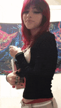 a woman with red hair is holding a book in front of a tapestry