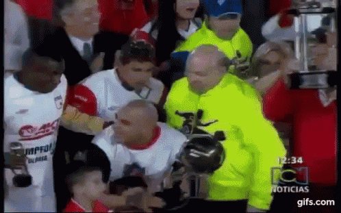a man in a yellow jacket is standing next to a man in a white shirt that says noticias
