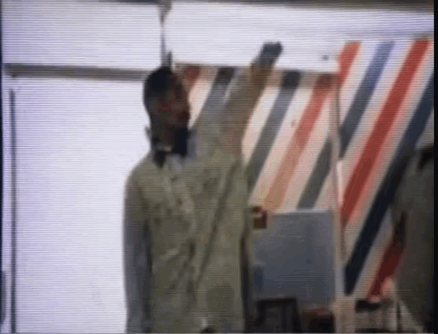 a man in a white coat is standing in front of a wall with red white and blue stripes
