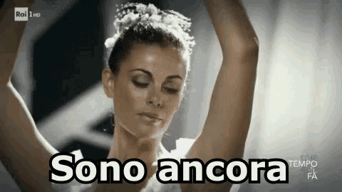 a woman in a white dress is dancing with her arms outstretched and the words sono ancora above her .