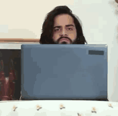 a man with long hair and a beard is sitting in front of a laptop computer