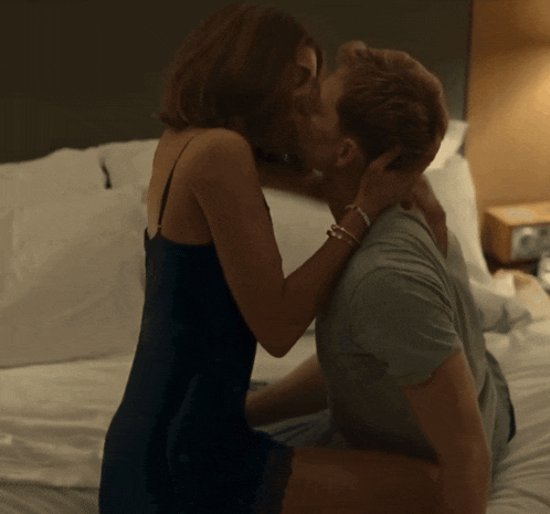a man and woman are kissing on a bed