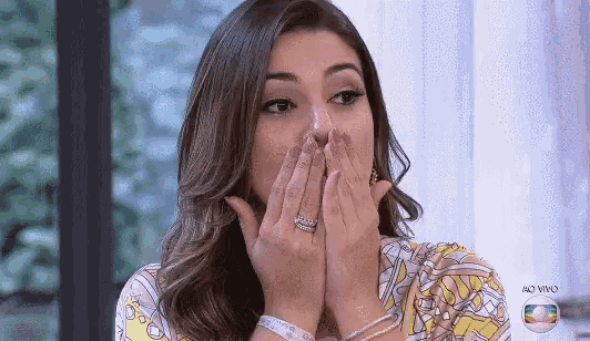 a woman is covering her mouth with her hands while wearing a ring .