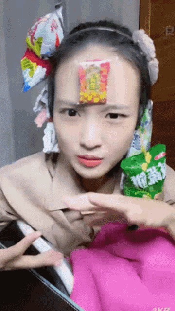 a woman with a bag of chips on her forehead is making a peace sign