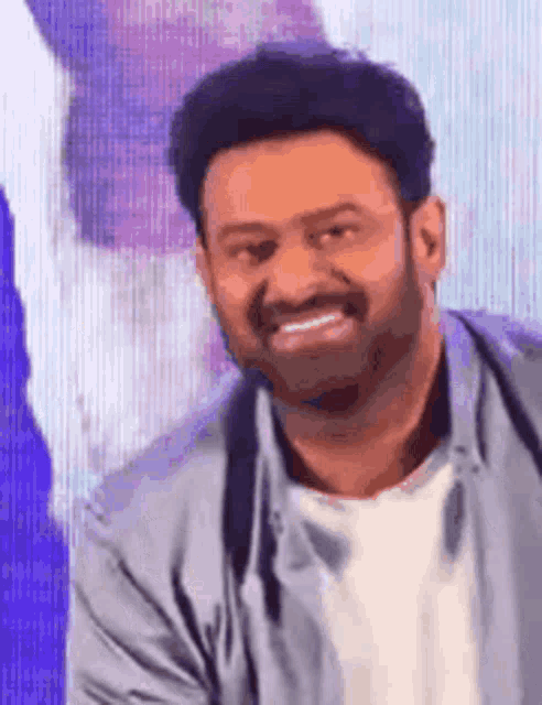 a man with a beard is smiling in front of a screen .