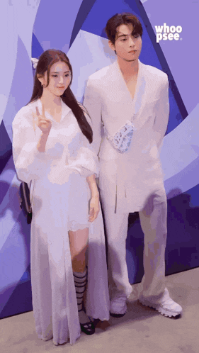a man and a woman standing next to each other in front of a sign that says whoop see