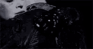 a black and white photo of a man and woman hugging each other in a dark room .