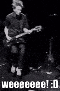 a man is playing a guitar on a stage in a black and white photo with the words weeeee ! : d .