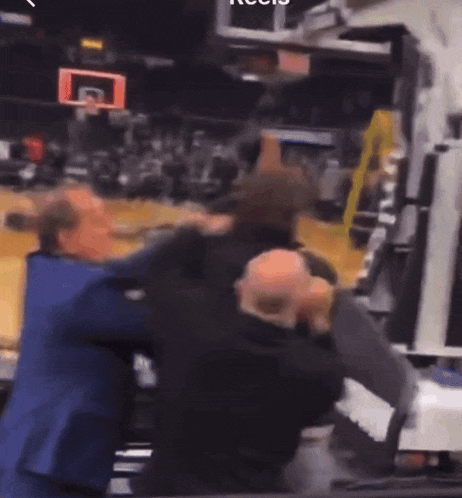 a group of men are fighting on a basketball court in front of a scoreboard that says ' reebok '