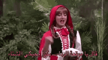 a woman dressed as little red riding hood is standing in the woods holding a plate .