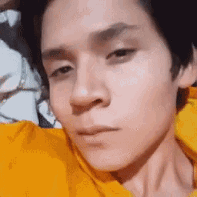 a close up of a person 's face in a yellow shirt .