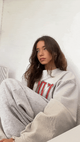 a woman wearing a grey sweatshirt that says ' ny ' on it