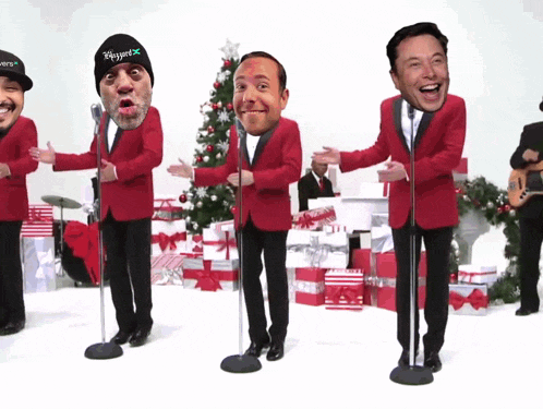 a group of men in red suits are singing into microphones