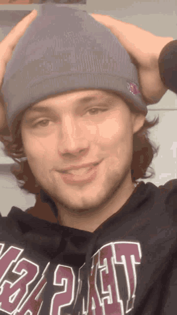 a man wearing a purple beanie and a black sweatshirt with the word gap on the front