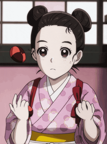 a little girl in a pink polka dot kimono is holding a red ball in her hair