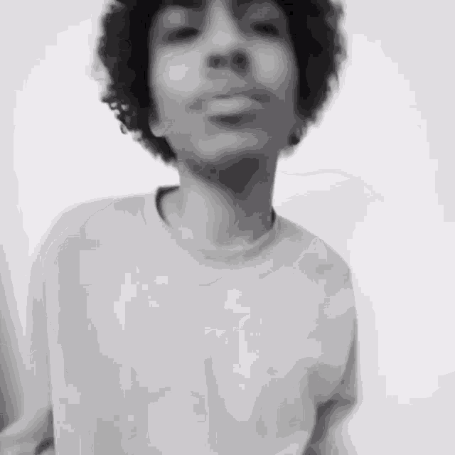 a black and white photo of a man with curly hair wearing a sweater .