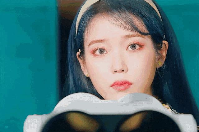 a woman with blue hair is looking at something