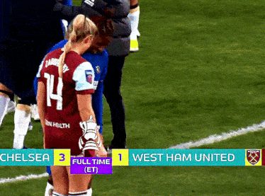 a soccer player with the number 14 on her jersey stands on the field