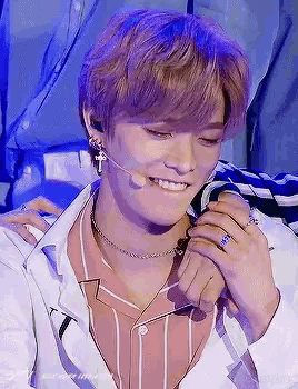 a young man wearing a striped shirt and a microphone is smiling