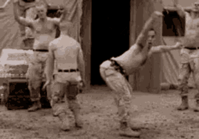 a group of men in military uniforms are stretching their arms in the dirt