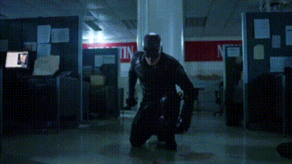 a man in a black hoodie is standing in a dark room holding a knife