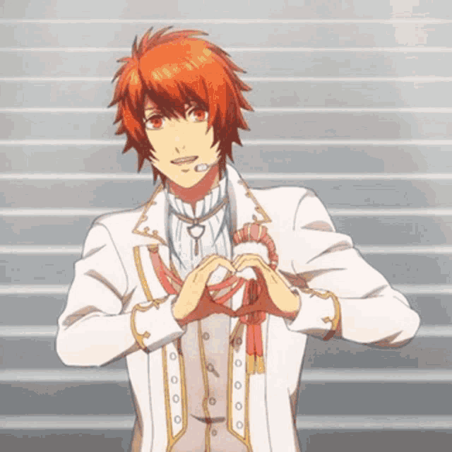 a boy with red hair is wearing a white suit and making a heart with his hands