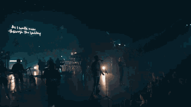 a group of people are singing on a stage in front of a crowd
