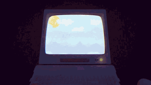 a computer monitor shows a blue sky with clouds and mountains