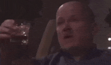 a bald man is drinking from a bottle with a label that says ' pilsner ' on it