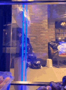 a room with a brick wall and a blue light behind a glass door