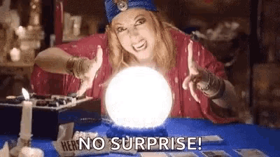 a fortune teller is sitting at a table with a crystal ball in her hand .
