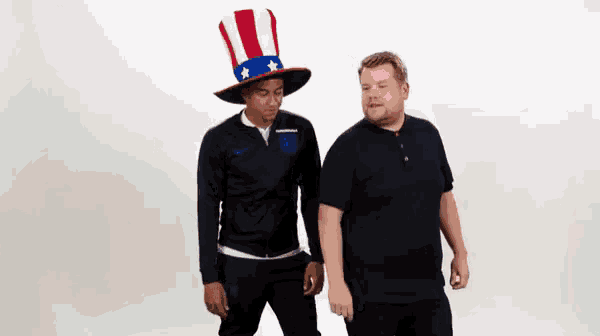 a man wearing an uncle sam hat is standing next to another man wearing a black shirt .