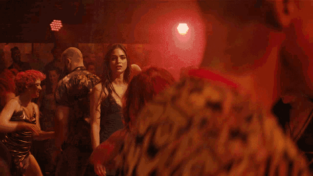 a woman in a black dress is dancing in a dark room