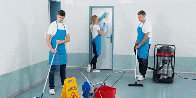a group of janitors are cleaning a room with mop , broom , and vacuum cleaner .