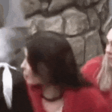 a woman in a red shirt is sitting next to another woman in a black shirt .