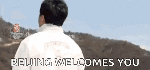 a man in a white jacket is standing in front of a sign that says beijing welcomes you .