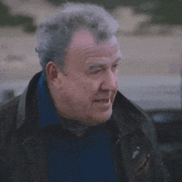 a man with gray hair and a blue shirt is wearing a brown jacket