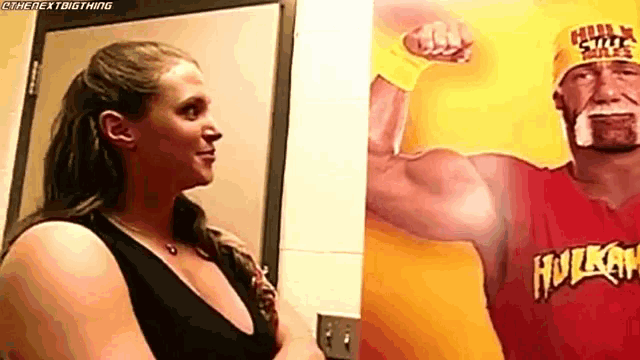 a woman is standing next to a picture of hulk hogan in front of a door .