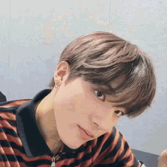 a close up of a young man wearing a striped shirt and earrings .