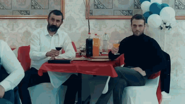 two men sit at a table with a red table cloth