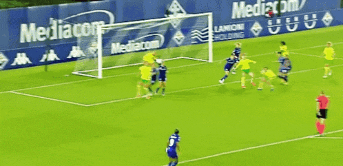 a soccer game is being played in front of a wall that says mediacom on it