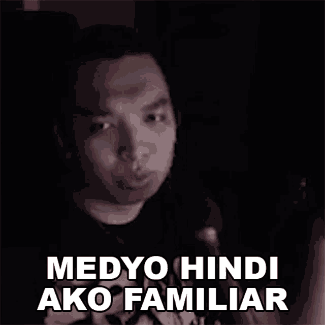 a man is talking into a microphone in a dark room and says medyo hindi ako familiar .