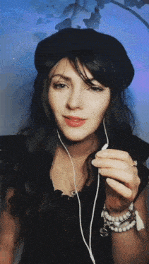 a woman wearing a black beret and earbuds looks at the camera