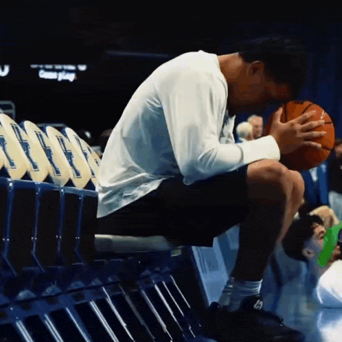 a man sits on a bench with a basketball in his hand