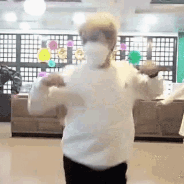 a man wearing a white sweater and a white mask is dancing in a room .