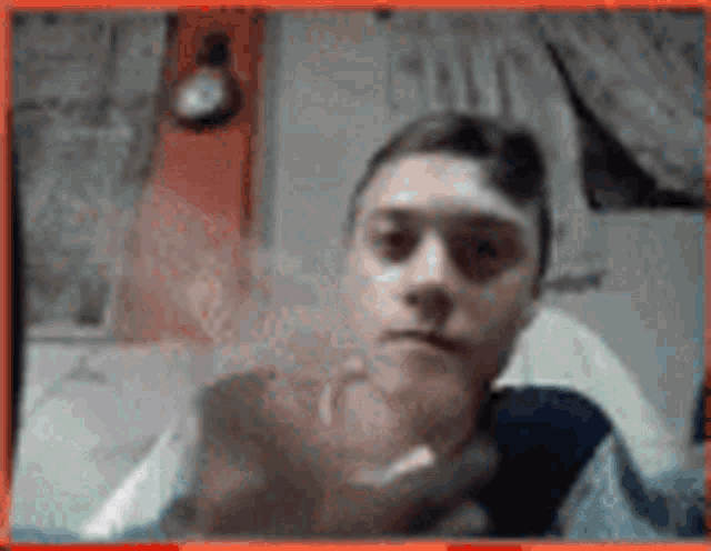 a young man is sitting on a bed holding a remote control .