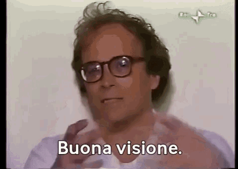 a man wearing glasses and a white shirt is making a funny face and saying buona visione .