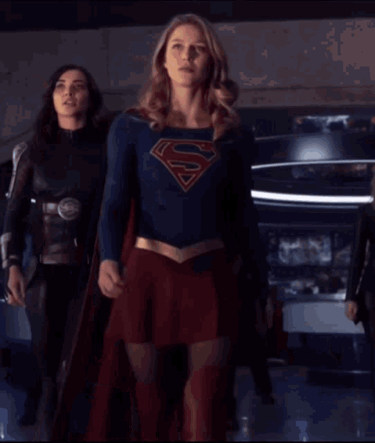 a woman in a superman costume stands in a room