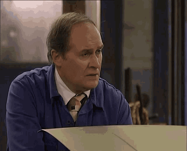a man wearing a blue shirt and tie is looking at something